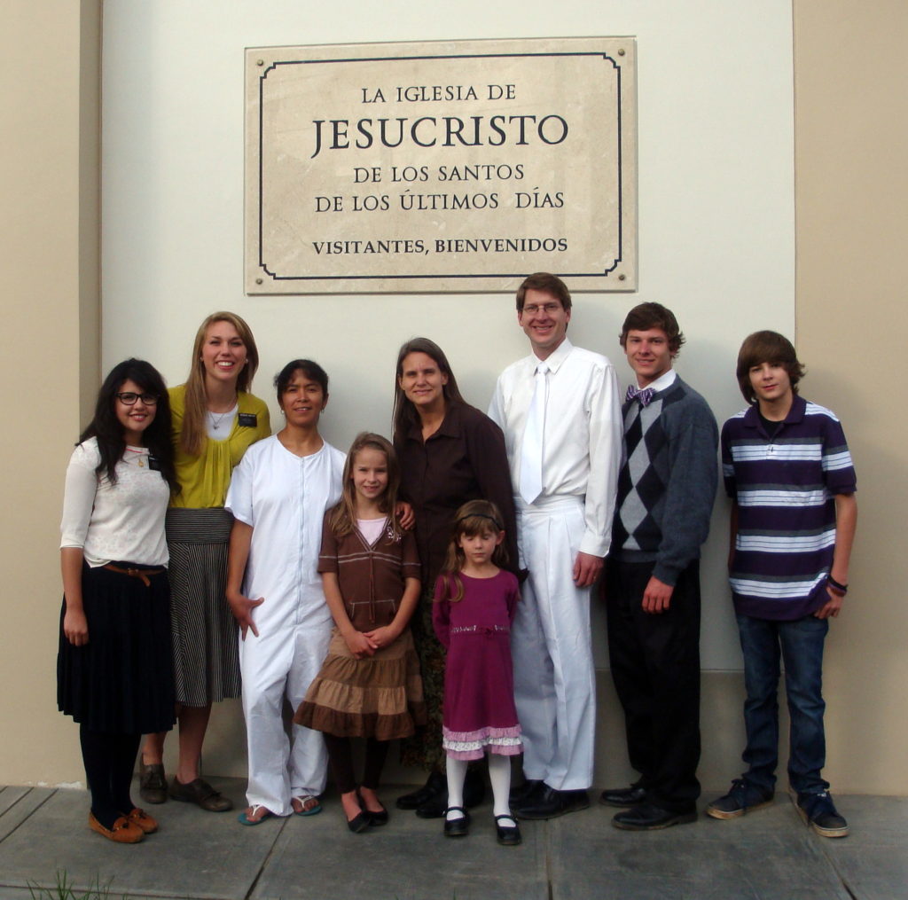 Our family with the sister missionaries and a new convert in baptismal clothes under the name plaque in front of the chapel